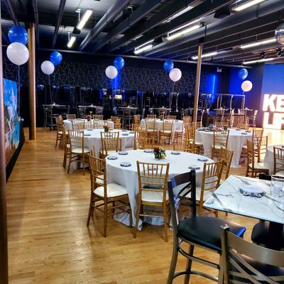 Event space decorated with blue and white balloons and tables set up for a gathering.