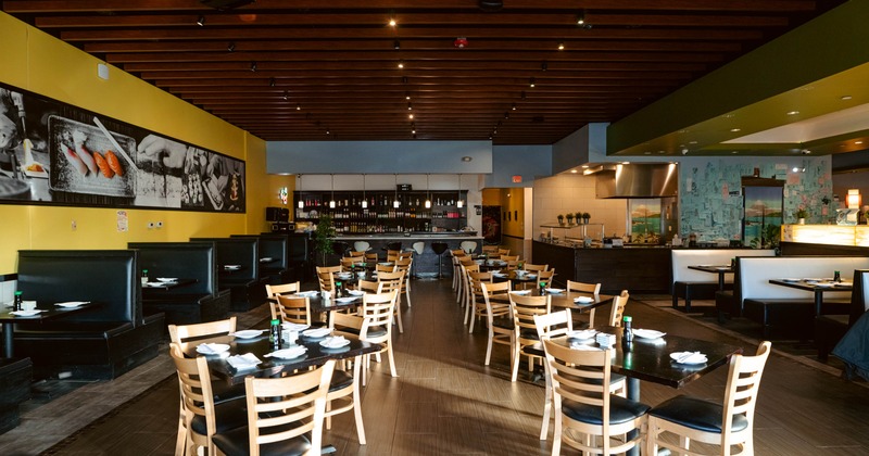 Interior, dining area, tables for four, seating booths rows on the left and right, bar in the back