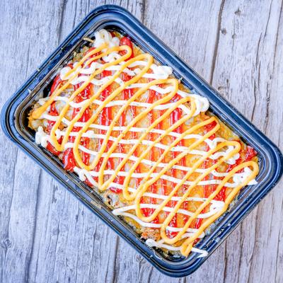 Layerd dish with fries and meat, topped with cheese and a savory sauce.