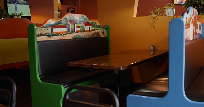 Interior, padded seating booths with wooden top table, Mexican motif decoration