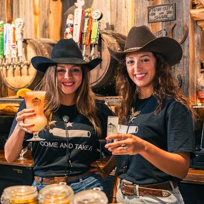 Two smiling persons holding drinks.