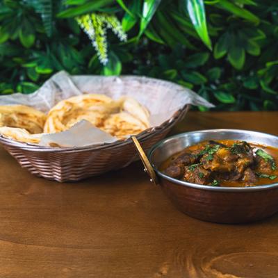 Goat curry served with a basket of Indian flatbread.