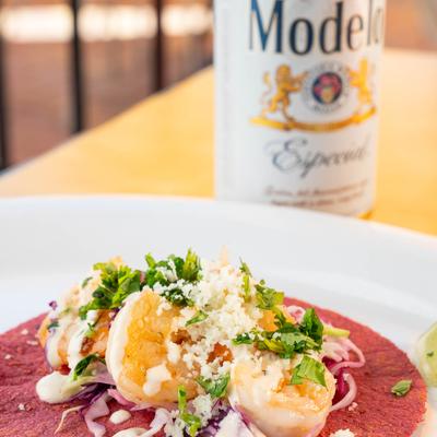 Shrimp taco topped with cabbage, red onion, cilantro, queso, and chipotle crema.