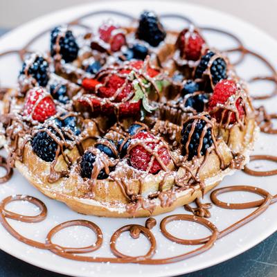 Belgian waffle with mixed berries, chocolate drizzle, and powdered sugar.