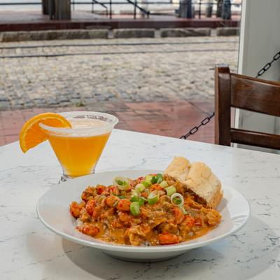 Crawfish Etouffee meal and a drink on a table outside.