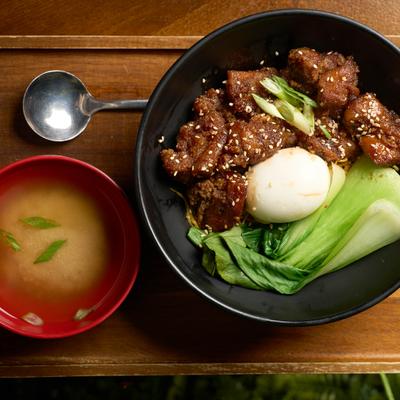 Rice bowl with sesame beef, soft egg, bok choy, and a bowl of miso soup.