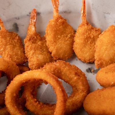 Sampler platter featuring fried shrimp and onion rings, close-up.