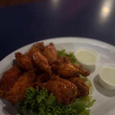 Buffalo chicken wings with lettuce and cups of ranch dressing.