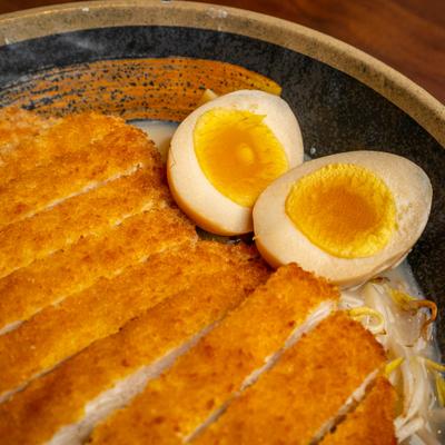 Chicken Katsu Ramen with a soft-boiled marinated egg, close-up.