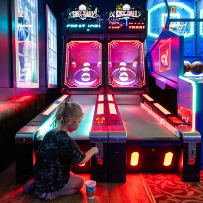 Child playing arcade skee ball game.