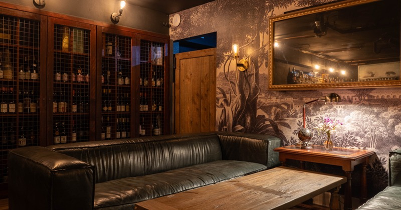 Cozy lounge with dark leather sofas around a wooden table, dim lighting