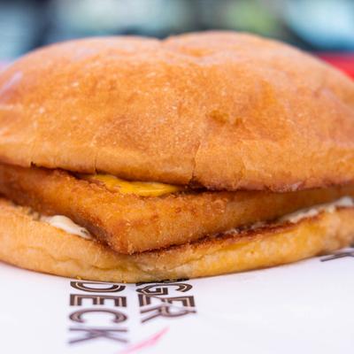 A close-up of a breaded fish filet sandwich in a soft bun.
