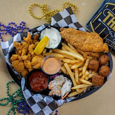 Basket with fried catfish filets, shrimp, hushpuppies, fries, coleslaw and dipping sauces.
