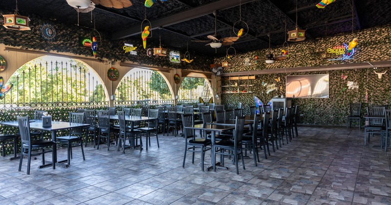 Interior of an open-air restaurant with black wooden tables and chairs