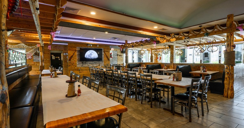 Interior - wooden tables, black leather booths, a large wall-mounted screen, nautical decorations