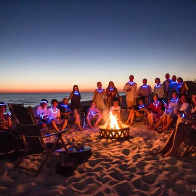 People on the beach around a fire pit.