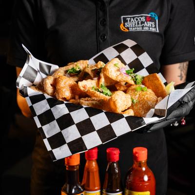 Fried pork skin with cilantro garnish served on checkered paper.