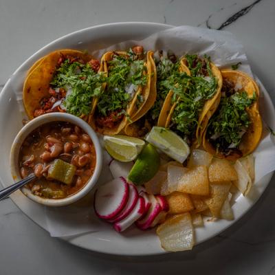 Marinated pork tacos, with onions and cilantro, served with onions, radish, beans.