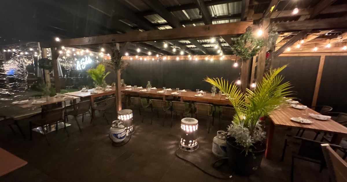 Patio featuring set tables and chairs illuminated by soft lights