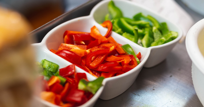 Cut red and green peppers in a three compartment bowl, closeup
