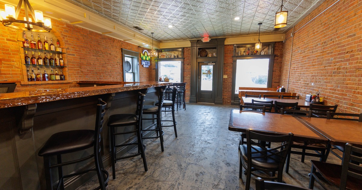 Rustic bar interior with exposed brick walls, a wooden bar, and natural light