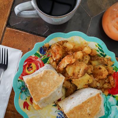 Smoked Brisket Burrito served with crispy smashed potatoes and a coffee.