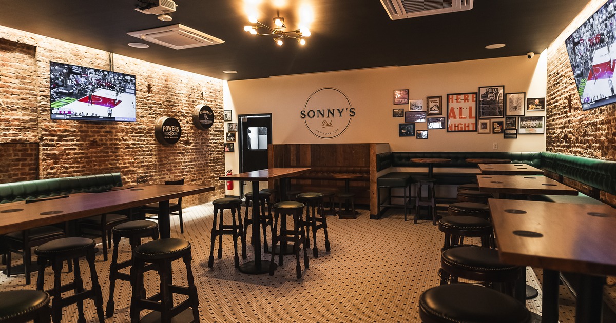 Sports bar interior space, high tables, stools, booth seating along the walls, and TVs on the walls