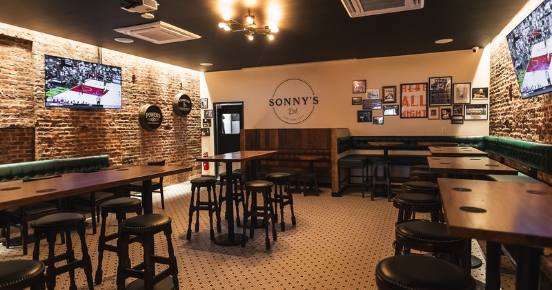Sports bar interior space, high tables, stools, booth seating along the walls, and TVs on the walls