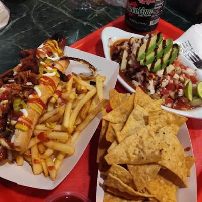Tray of food including loaded hot dog, french fries, nachos and ceviche.
