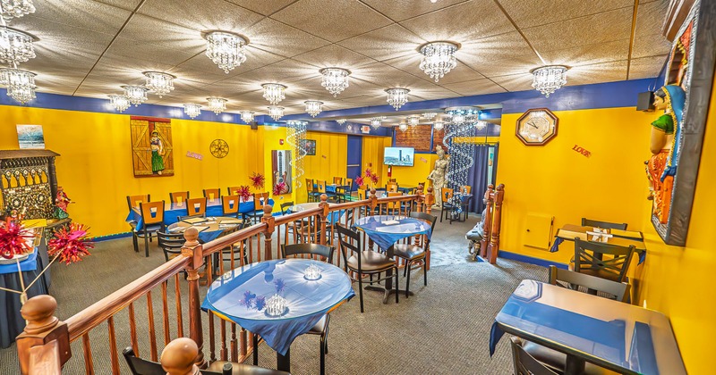 Spacious, colorful and cozy interior dining area in Indian style with tables ready for guests