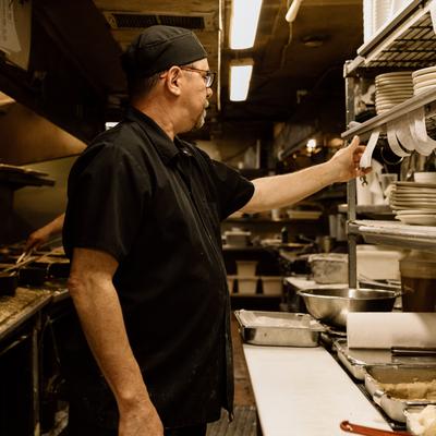 Chef working in a commercial kitchen next to a stainless steel shelf stack.