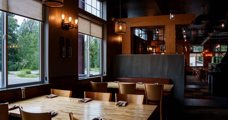 Interior view of a modern restaurant featuring a wooden table set for dining, large windows
