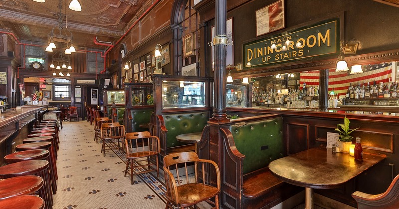 Vintage pub interior with ornate tin ceiling, wooden booths, and green leather seats