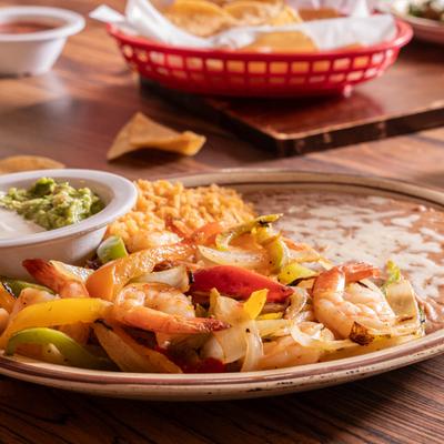 Shrimp Fajitas, with onion, bell peppers, tomato, garlic, rice, beans, sour cream, and guac.