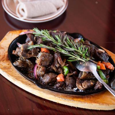 Sauteed tender beef strip with onions, peppers, and rosemary sprig.