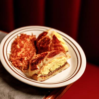 Grilled breakfast sandwich with eggs and cheese, served with a side of hashbrowns.