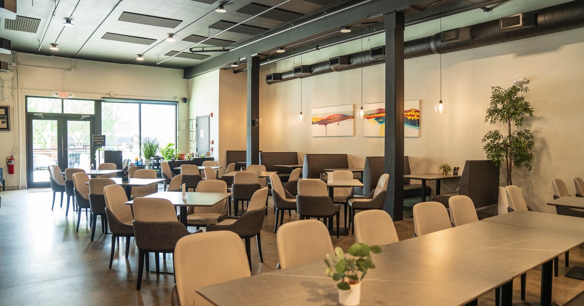 Restaurant interior with modern decor, featuring light brown chairs, wooden tables