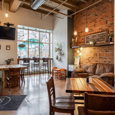 Interior with wooden tables, pendant lights, and brick walls.