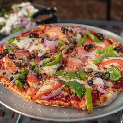 Veggie pizza sits on a metal tray.
