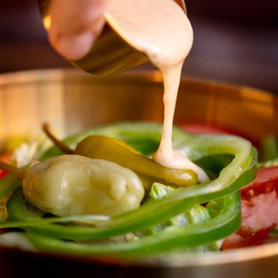Salad with dressing being poured on top.