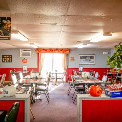 A cozy diner with tables, chairs, decorative plants and autumn decorations.