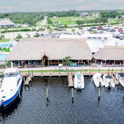 Aerial view of a tiki-style waterfront bar with boats docked along the pier.