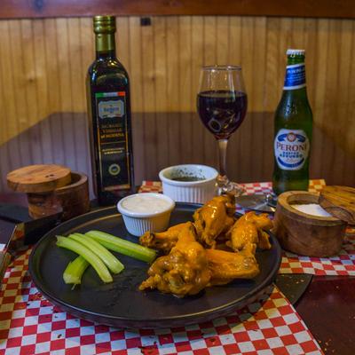 Buffalo wings with celery and ranch sauce, accompanied by drinks and spices.