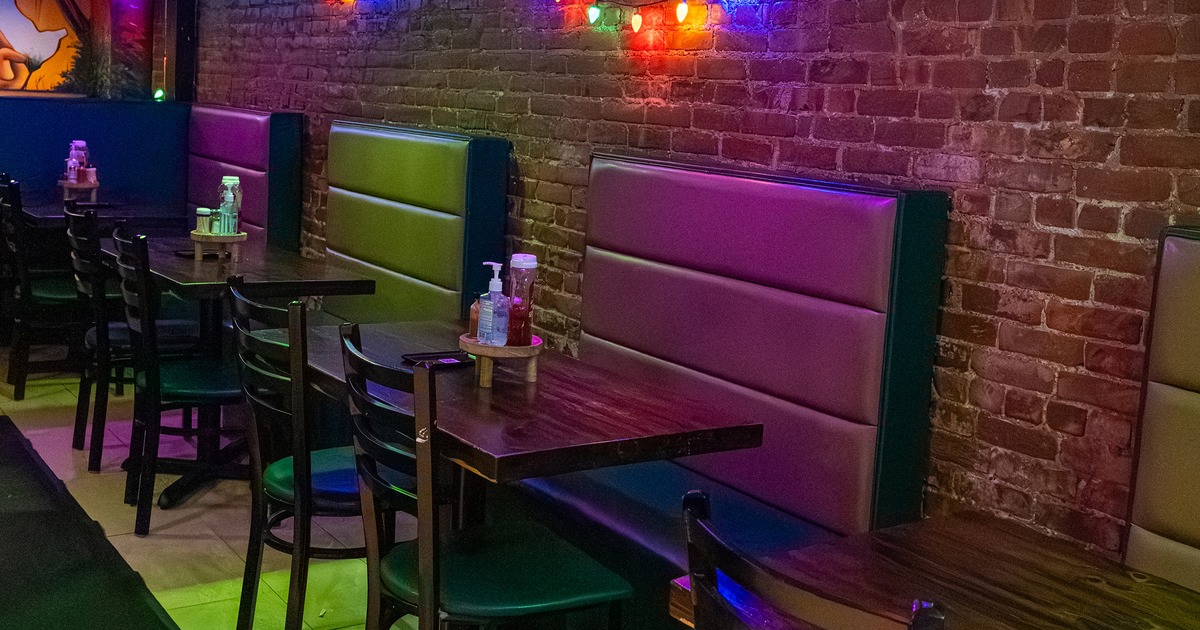 Interior seating area, wooden tables and chairs and upholstered seats lined along the wall