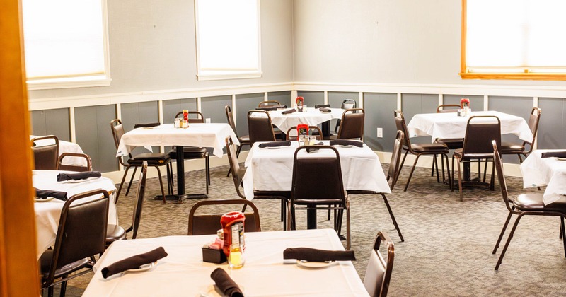 Interior seating area with chairs and tables set with tablecloths