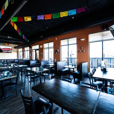 Dining room with booths, tables, large windows, and papel picado banners.