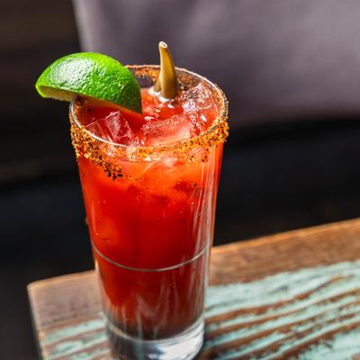 Cocktail in rimmed highball glass, garnished woth lime wedge.