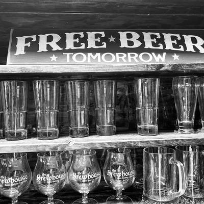 Brewhouse shelf with 12 oz glasses and tulip glasses with sign that says Free Beer Tomorrow.