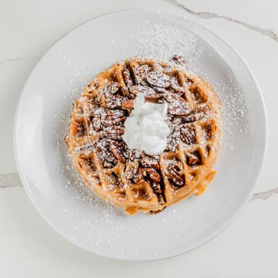 Pecan waffle topped with whipped cream.