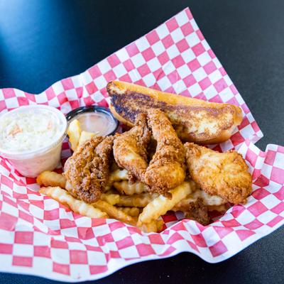 Chicken fingers plate with fries, coleslaw, toasted bread and a dip.